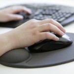 GERMANY, BONN, Health at work, Our picture shows a hand with computer mouse on an ergonomic mousepad with built-in wrist rest made of silicone gel before a computer keyboard.